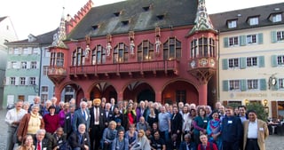 Group photo of the participants on the square in front of the red Historisches Kaufhaus in Freiburg