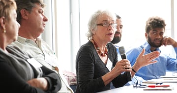 Participant speaking into a microphone during a discussion round
