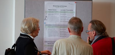 Participants reading the programme for the networking day on a pin board