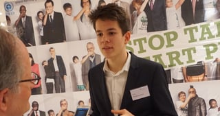 Felix Finkbeiner in conversation in front of a Plant-for-the-Planet poster with the slogan "Stop talking. Start planting."