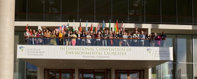 Participants with national flags on a balcony above a banner reading International Convention of Environmental Laureates, Freiburg Germany