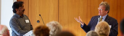 Two speakers on stage in front of a wooden wall at the 5th International Convention of Environmental Laureates