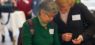 Two women with name badges looking at something together