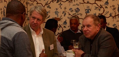 Participants talking at the reception in front of a patterned wallpaper