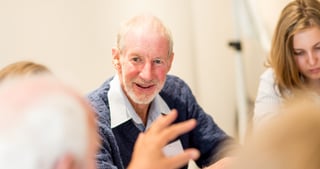 Smiling older man gesturing during a conversation at a table