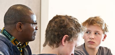 Man with glasses in conversation with two teenage boys
