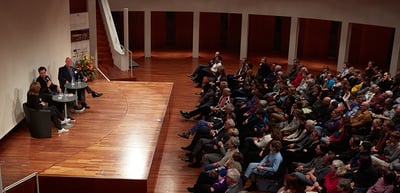 Podium talk on the stage of a large hall with a full audience