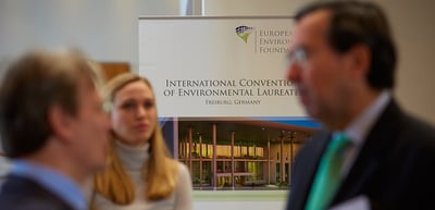 Participants talking in front of a banner of the International Convention of Environmental Laureates