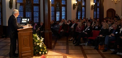 A speaker at the lectern in front of the audience in the hall of the Historisches Kaufhaus