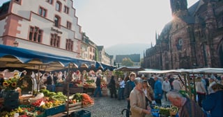 Farmers' market on the Cathedral Square in Freiburg with stalls of fruit and vegetables and the cathedral