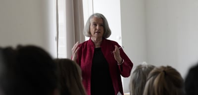 A woman in a red jacket giving an impulse lecture