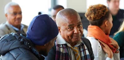 Smiling older man in a checked scarf among other participants