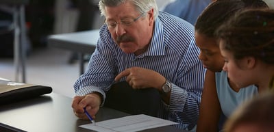 Man with glasses taking notes next to a young woman at a seminar table