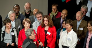 Group of participants with name badges standing close together, a woman in a red jacket in front