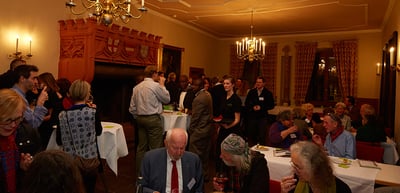 Participants at the reception in a historic hall with chandeliers and laid tables