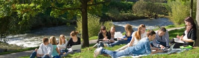 Students studying on a meadow on the bank of a river in Freiburg
