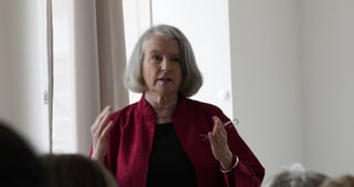 A woman in a red jacket giving an impulse lecture