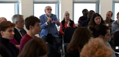 A man in the audience speaking into a microphone during a discussion